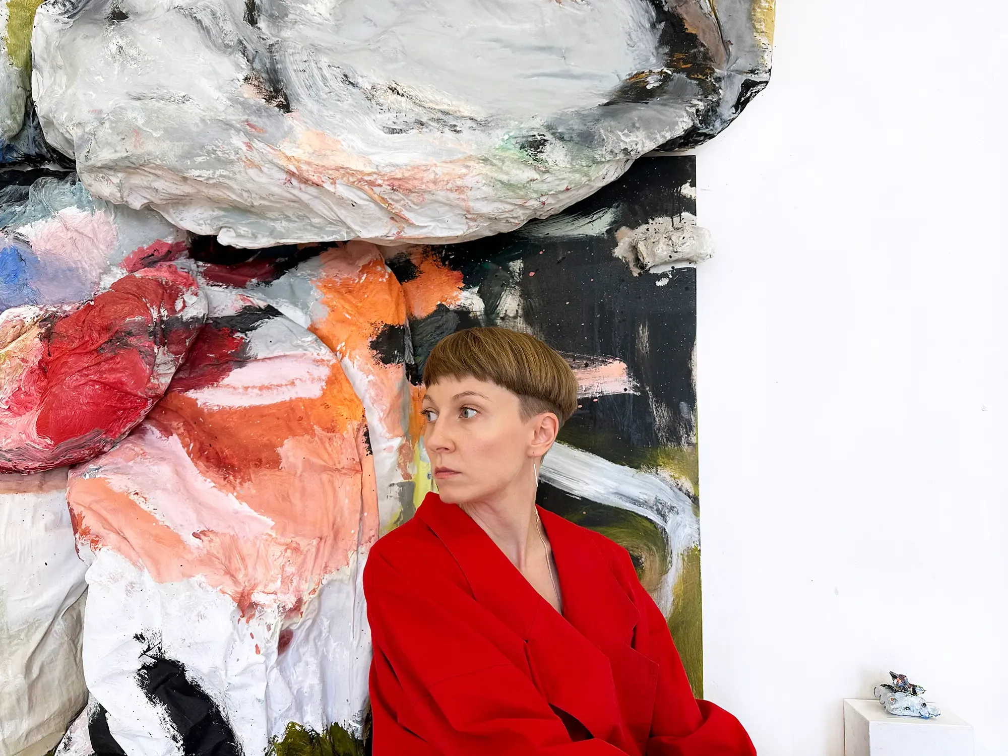 olga shcheblykina in red coat in front of her abstract art installation